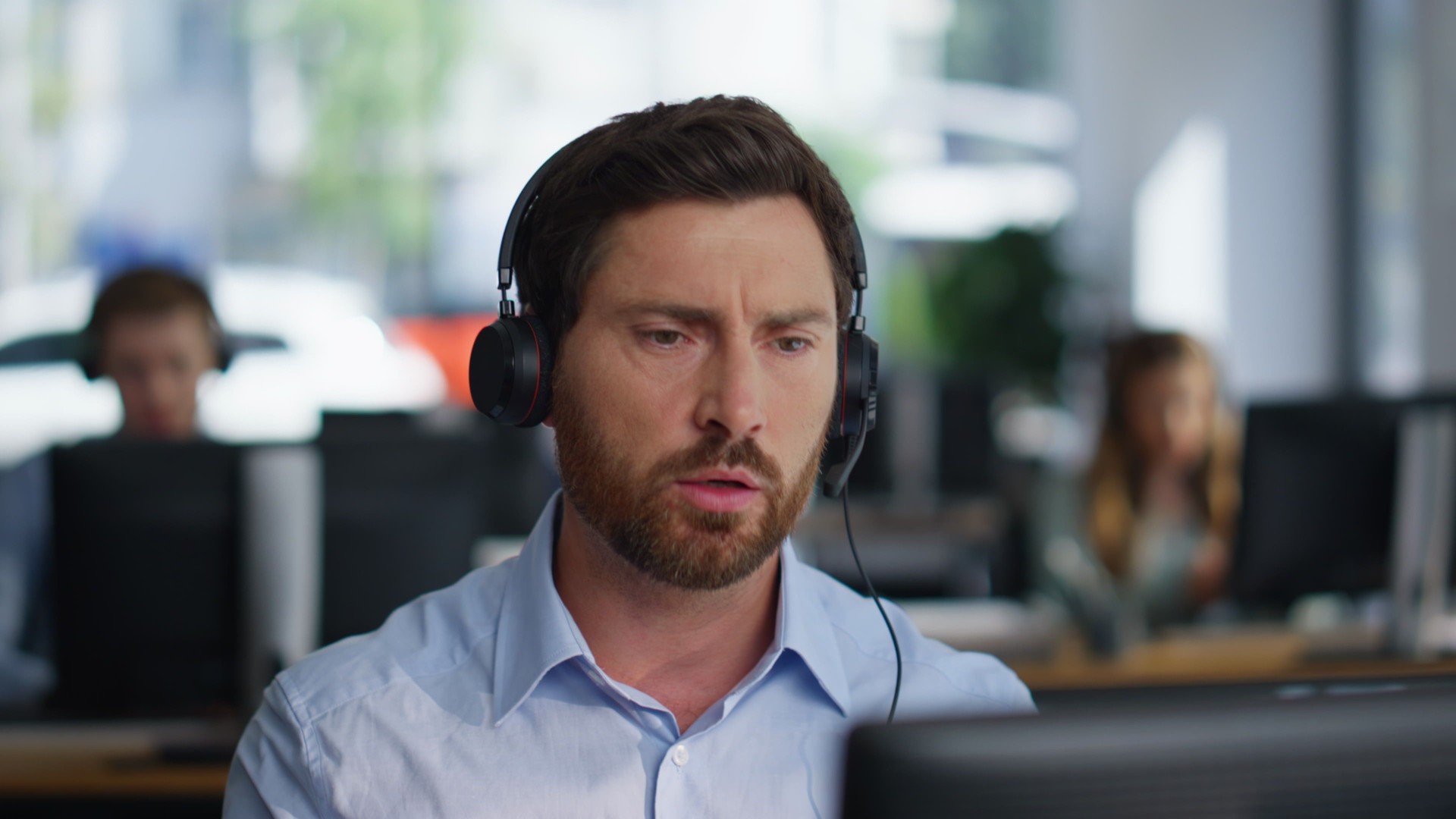 Serious helpdesk assistant talking headset in office coworking space closeup.
