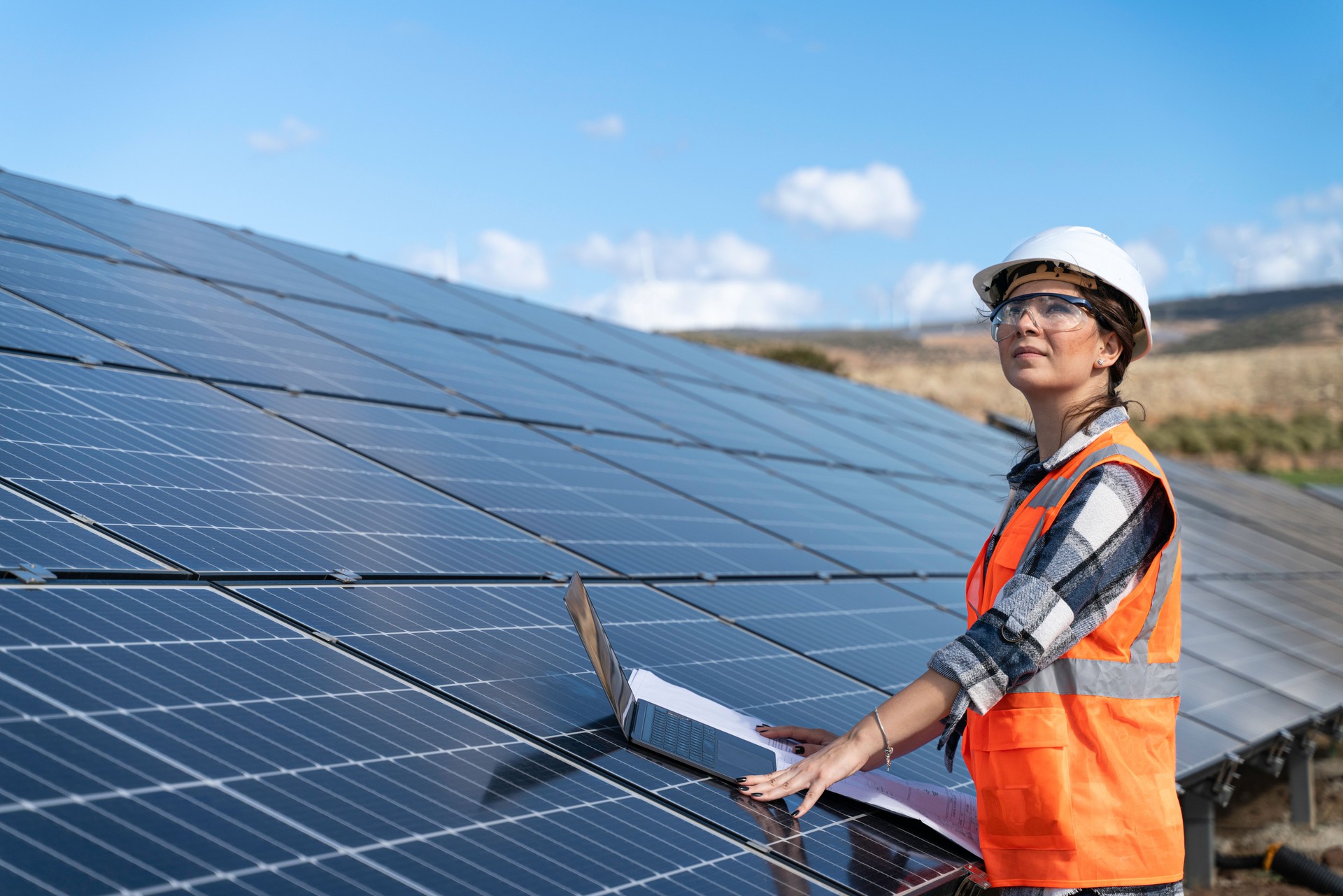 Young engineer inspect installation of solar panels installed check  with blueprint on the field, with recording inspection data on pc.