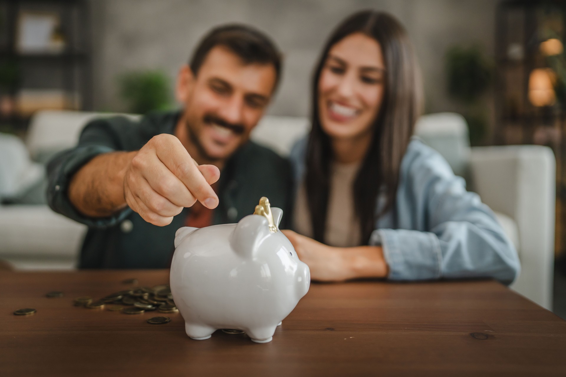 Adult couple save money coins in the piggy bank at home
